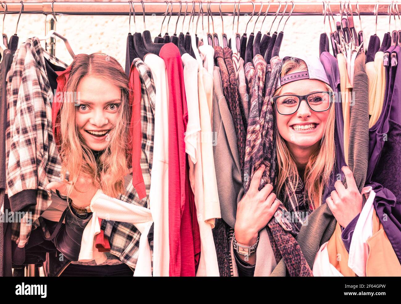 Young hipster women at clothes flea market - Best friends sharing fun time shopping in the city - Urban girlfriends enjoying happy life moments Stock Photo