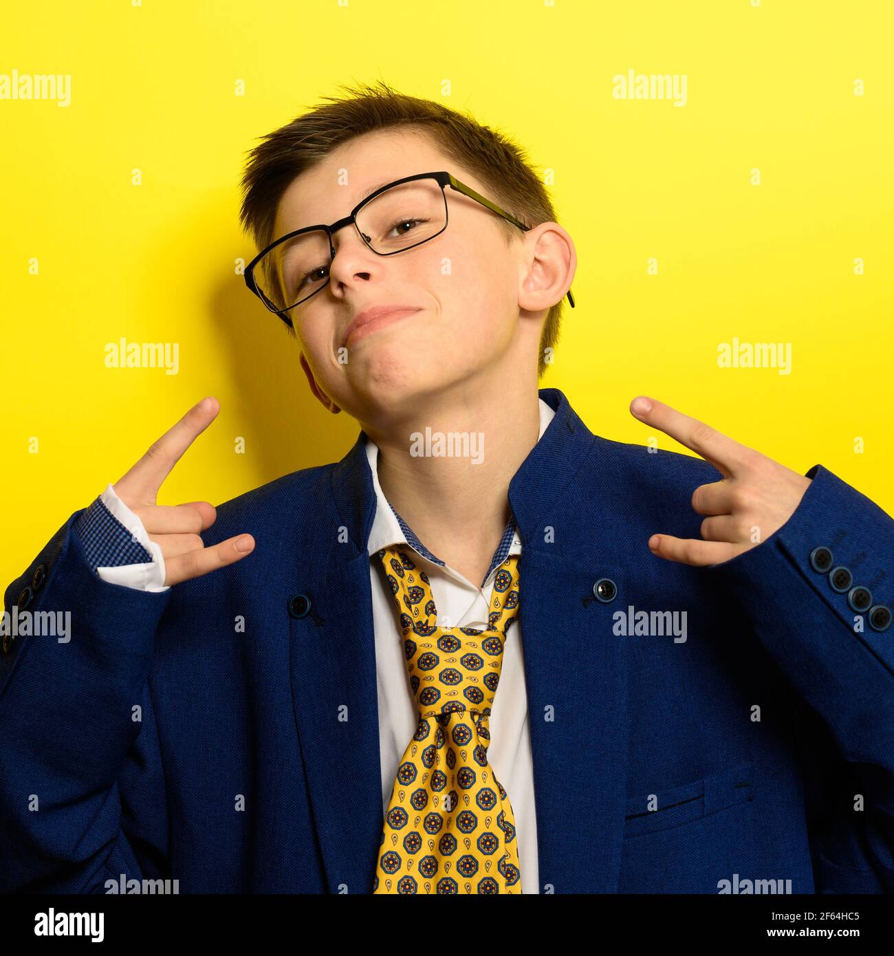 Attractive boy in an adult suit on a yellow background, a child's