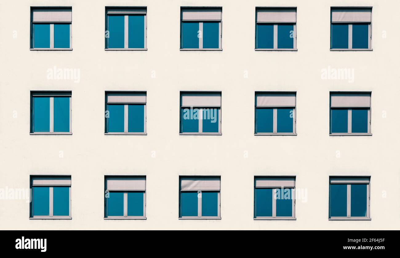 Multiple windows of a residential flat apartment building from the font with white cream walls, abstract modern architecture exterior, minimal ist urb Stock Photo