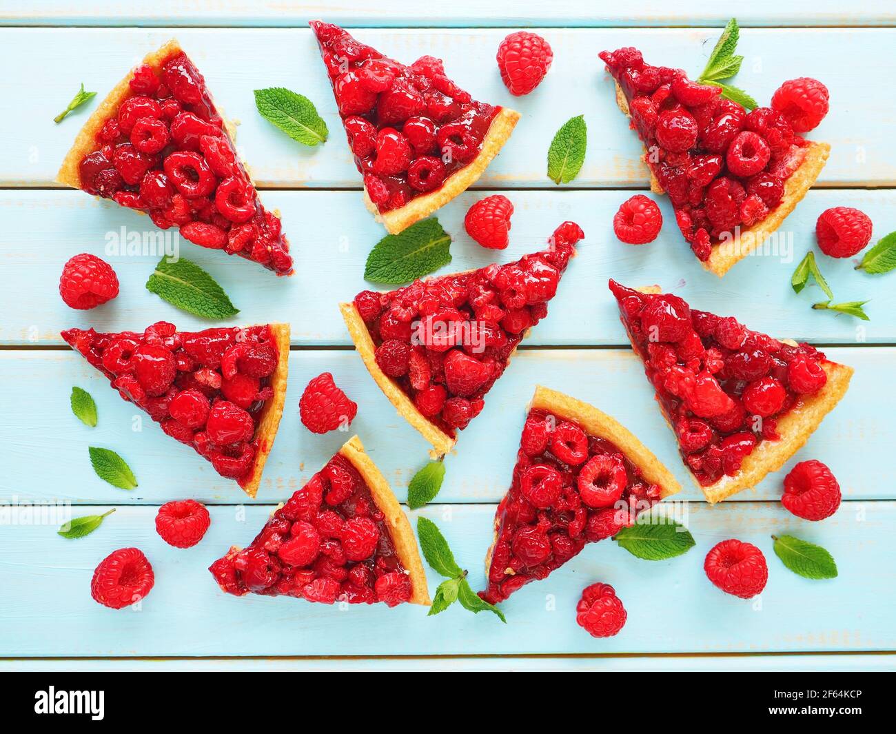Slices of homemade traditional sweet tart with raspberry and mint leaves on wooden background Stock Photo