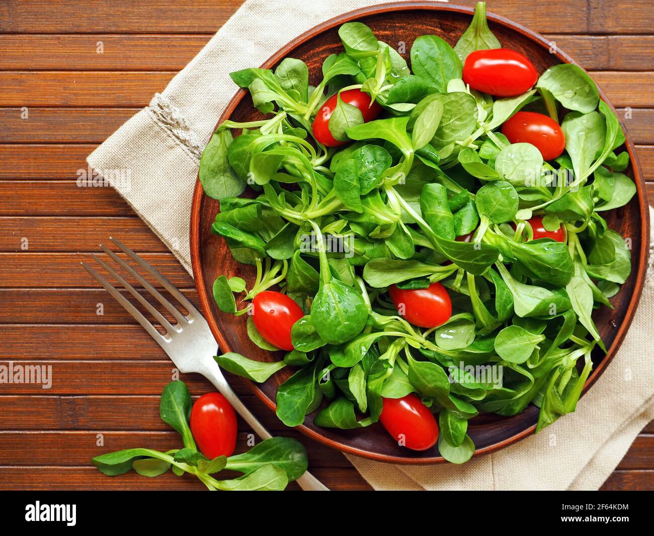 Wooden bowl with corn salad, lamb's lettuce and cherry tomatoes Stock Photo