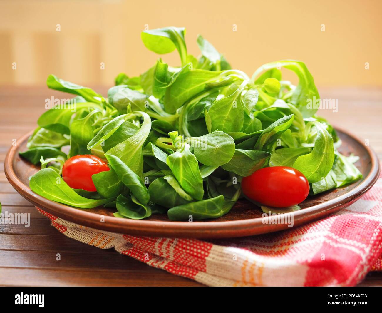 Wooden bowl with corn salad, lamb's lettuce and cherry tomatoes Stock Photo