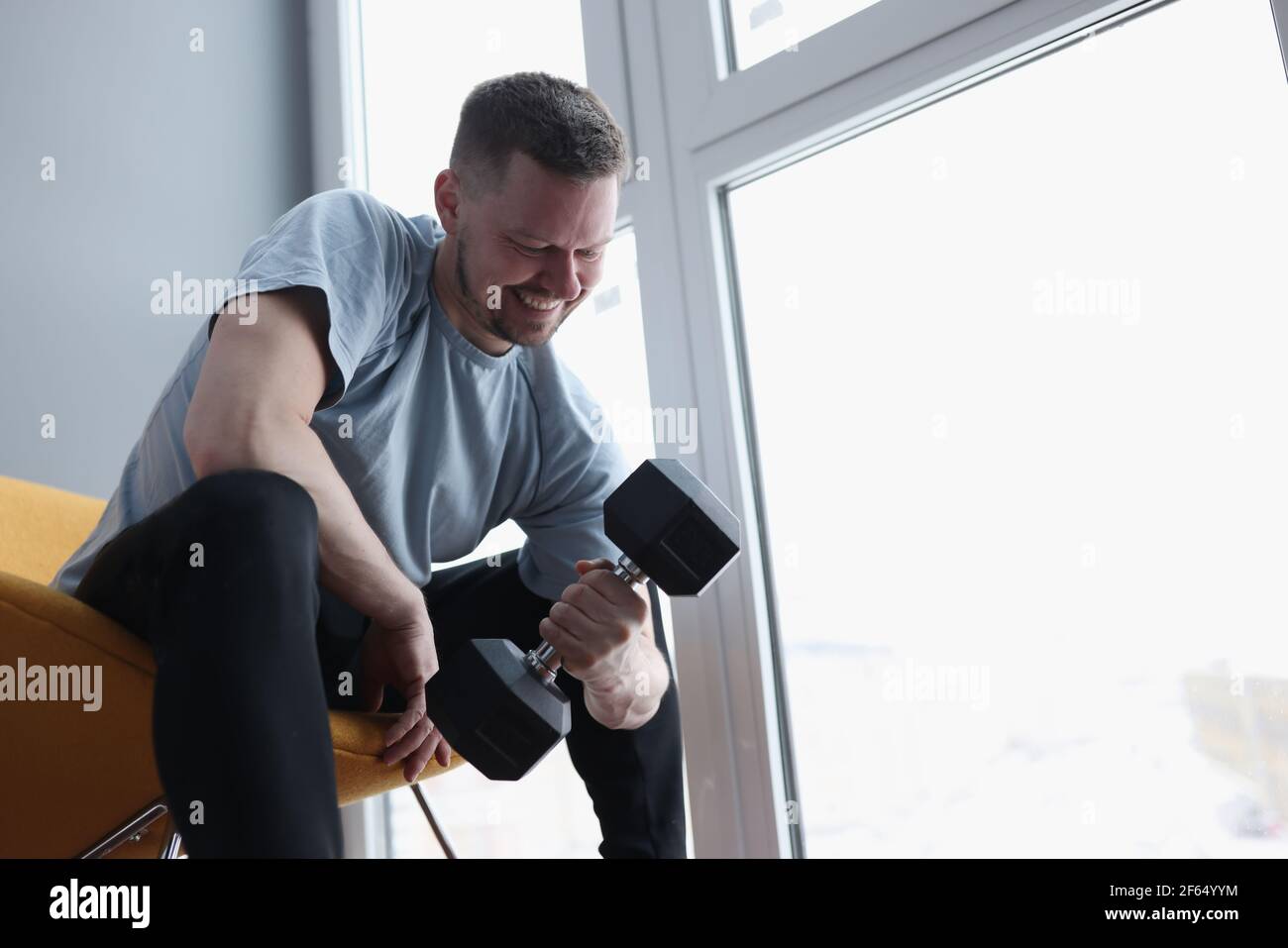 Man does exercises with dumbbells for biceps Stock Photo