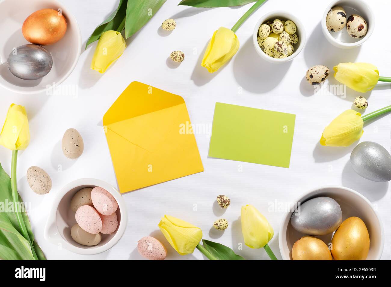 Colorful easter and quail eggs and tulips with envelope on white ...