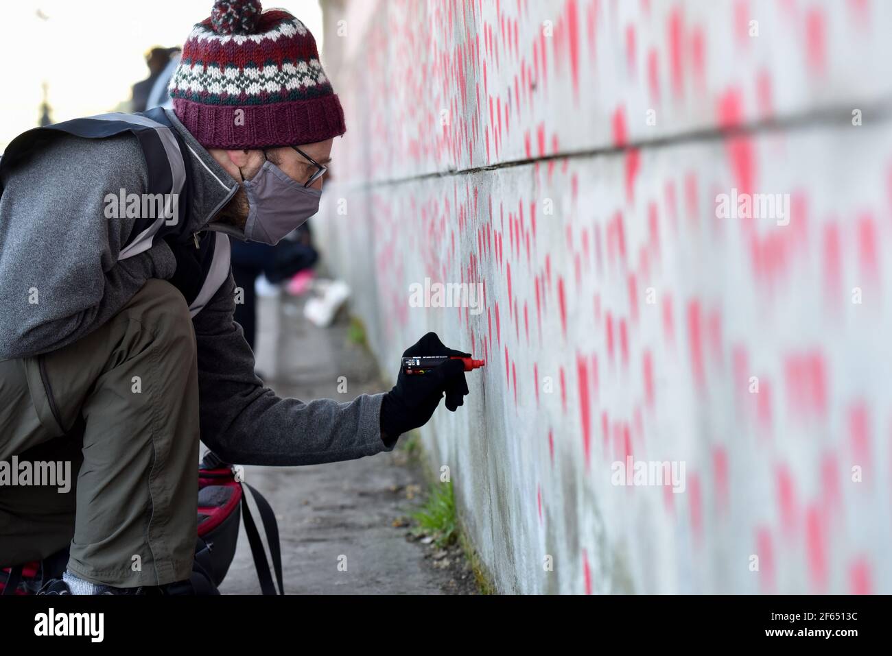 Westminster, London, UK. 30th Mar 2021. People work on the National Covid Memorial Wall opposite the Houses of Parliament. The wall is a being created by families and friends of those who have died. Credit: Matthew Chattle/Alamy Live News Stock Photo