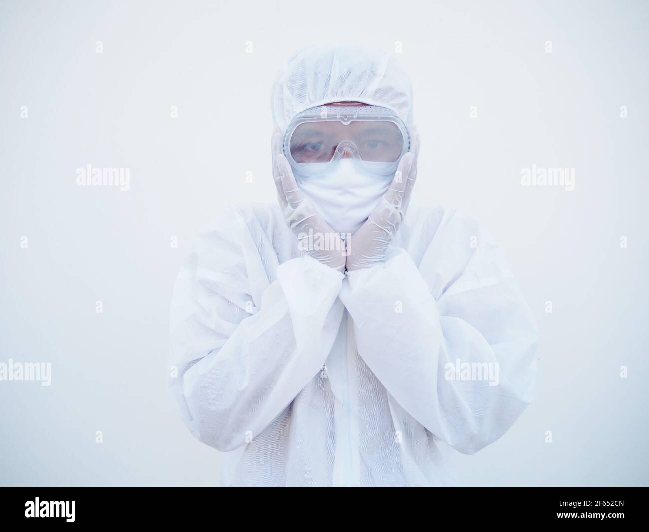 Asian doctor or scientist in PPE suite uniform covers ears with hands. Danger of coronavirus or COVID-19 concept isolated white background Stock Photo