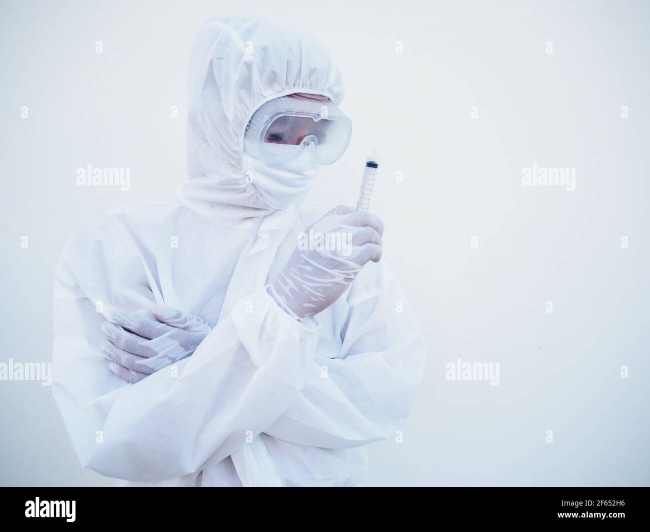 Asian doctor or scientist in PPE suite uniform holding medical injection syringe. coronavirus or COVID-19 concept isolated white background Stock Photo