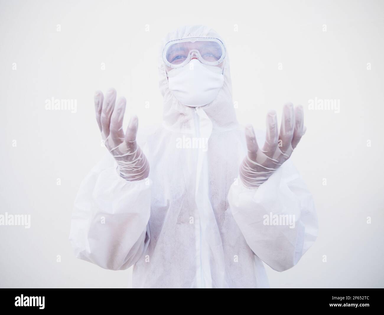 Closeup of asian male doctor or scientist in PPE suite uniform has stress and pray during an outbreak of coronavirus or COVID-19 isolated white backgr Stock Photo