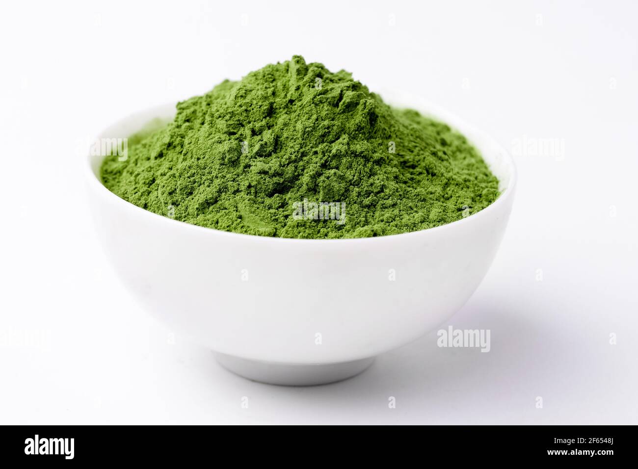 Green Barley Sprout grass and bowl of green detox powder isolated on white. Copyspace. Stock Photo
