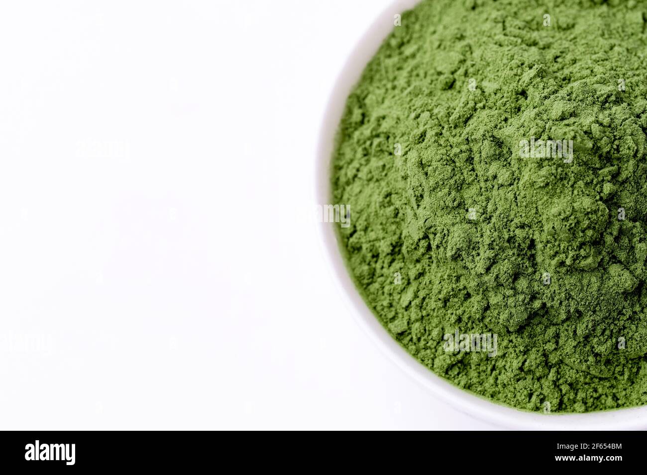 Green Barley Sprout grass and bowl of green detox powder isolated on white. Copyspace. Stock Photo