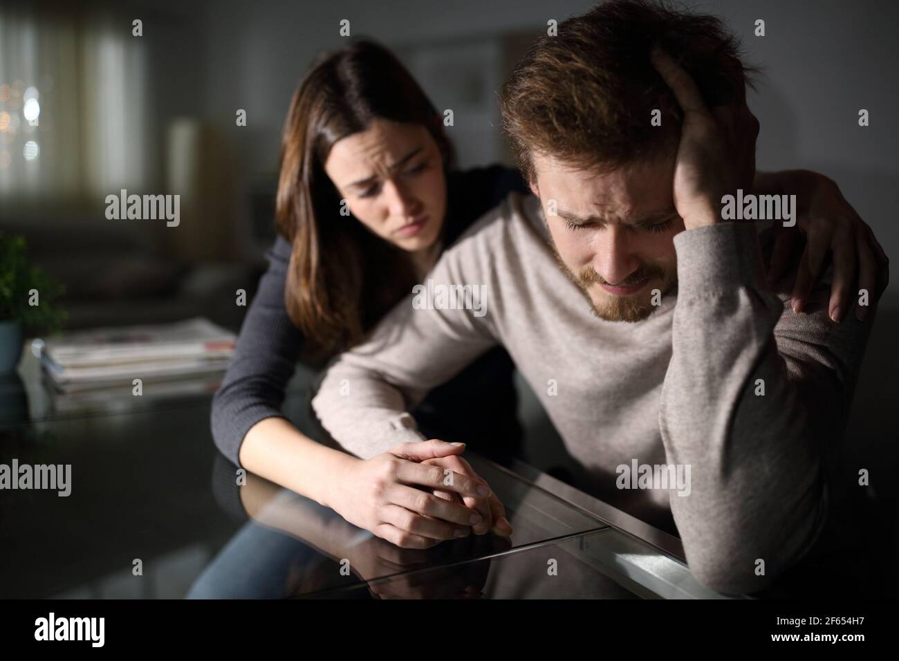 Sad man being comforted by his wife in the night at home Stock Photo