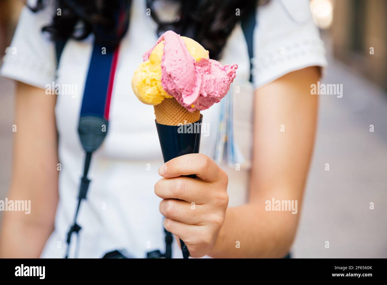 Hand of a tourist woman holding a big two flavored ice cream cone in the street Stock Photo