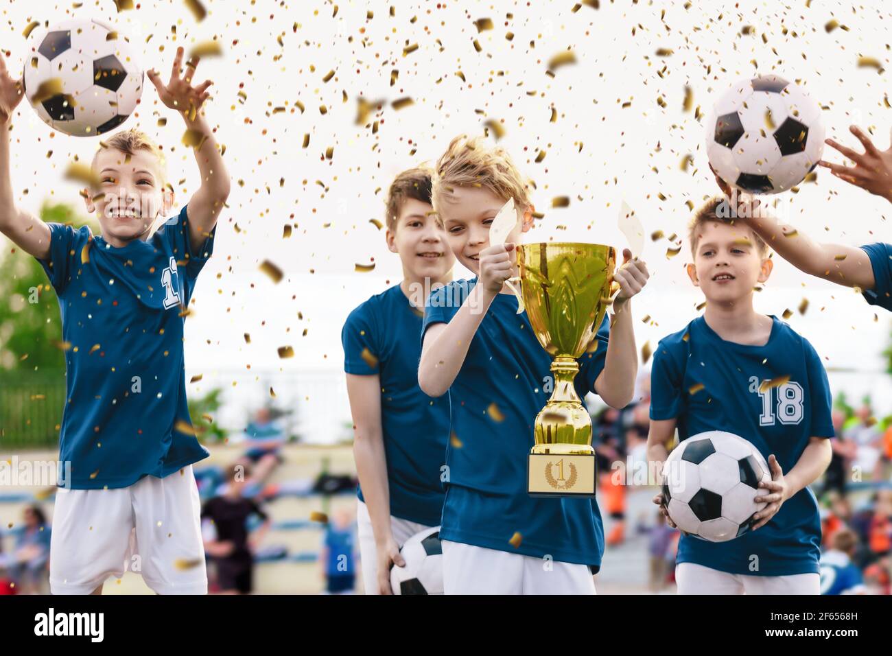 Soccer Team Celebration. Cheerful Children Celebrating Success in Football Tournament Game. Junior Sports Team Rising Golden Trophy on Confetti Celebr Stock Photo