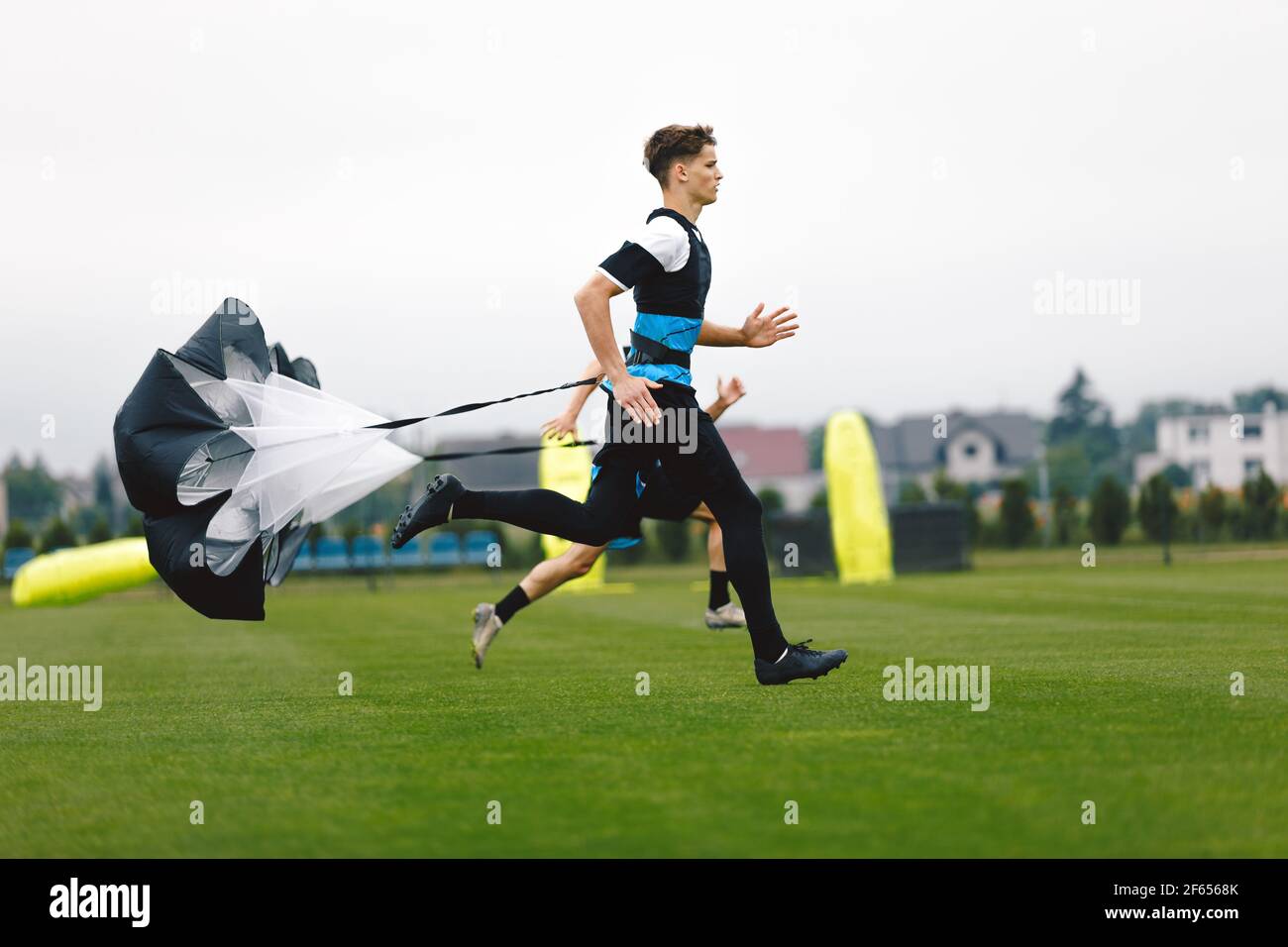 Junior Football Player Running with Parachute. Soccer Endurance and Strength Training. Player Speed Testing. Professional Soccer Strength Test. Young Stock Photo