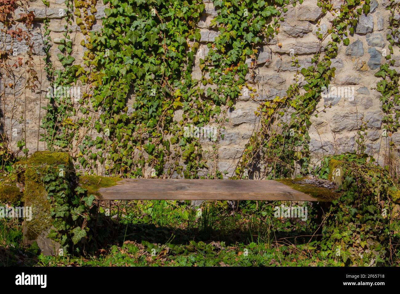 Old damaged and weathered bench in front of a natural stone wall ...