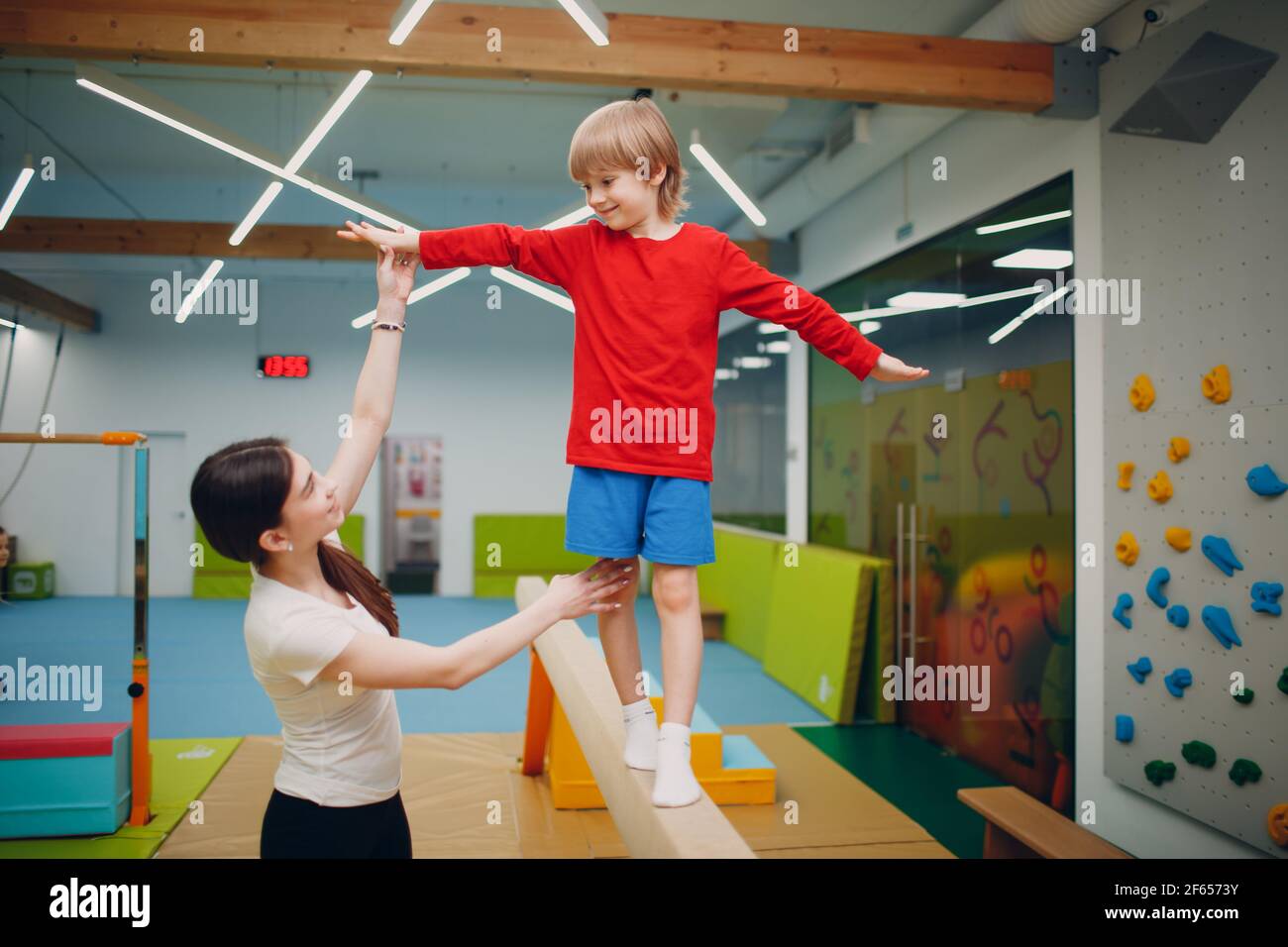 Kids doing balance beam gymnastics exercises in gym at kindergarten or elementary school. Children sport and fitness concept Stock Photo