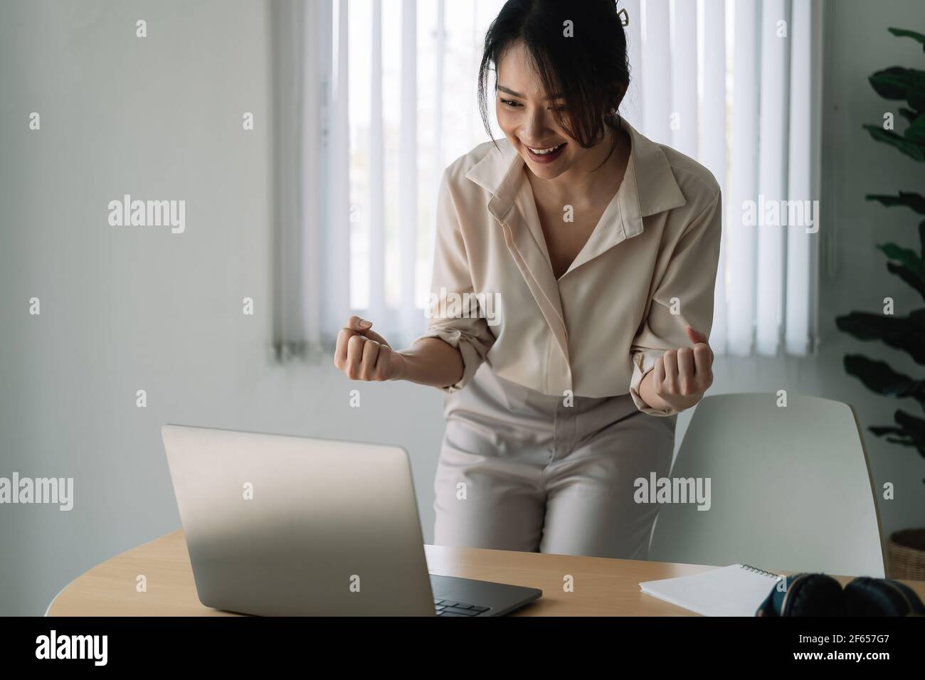 Excited Asian Businesswoman Celebrating Success At Workplace. Stock Photo