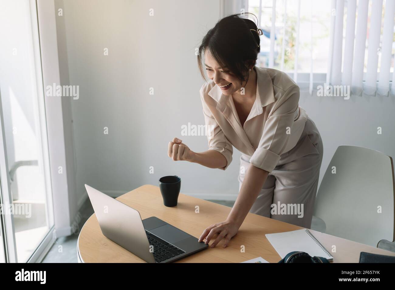 Excited Asian Businesswoman Celebrating Success At Workplace. Stock Photo