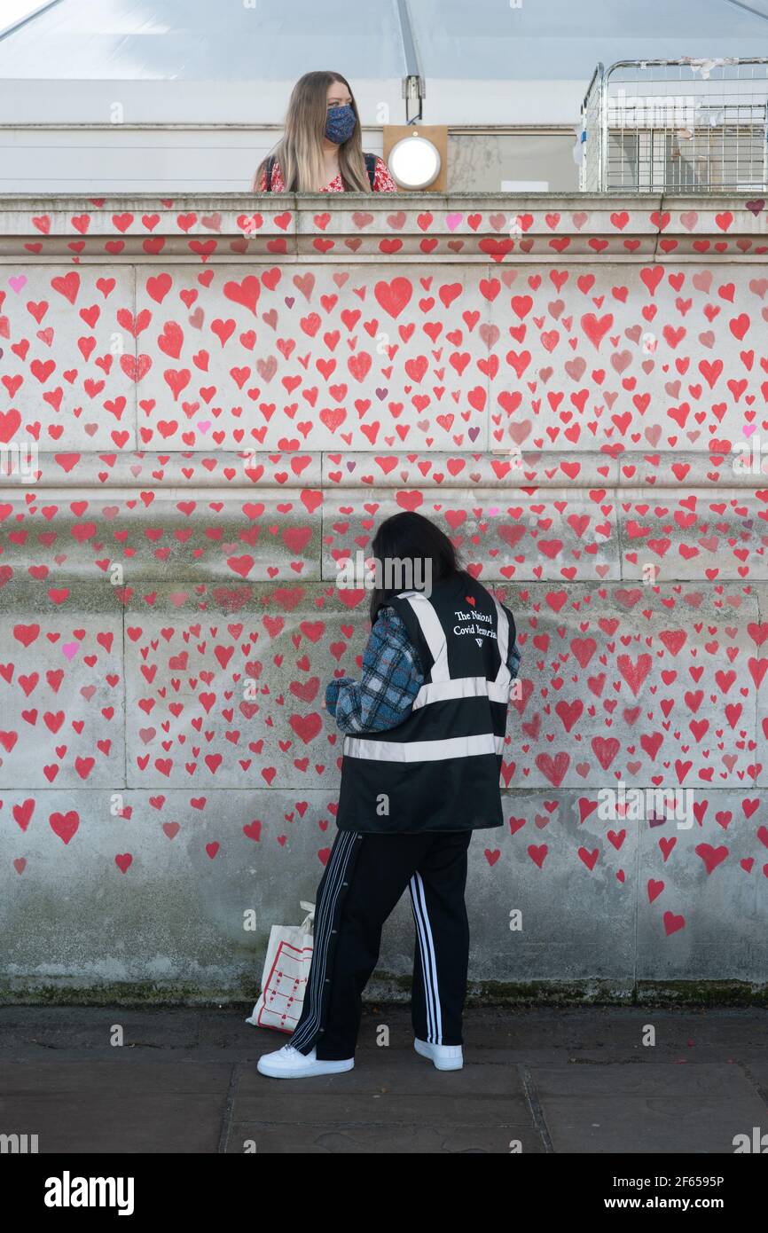 London, UK. 30th March, 2021. A memorial mural featuring nearly 150,000 red hearts C one for each UK covid death C will stretch for hundreds of metres, organised by the Covid-19 Bereaved Families for Justice group on the south bank of the Thames in London. Photo: Roger Garfield/Alamy Credit: Roger Garfield/Alamy Live News Stock Photo