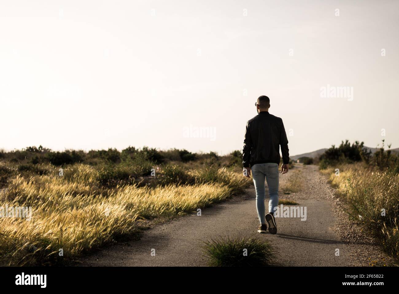 A person walking along a road at sunset. Stock Photo