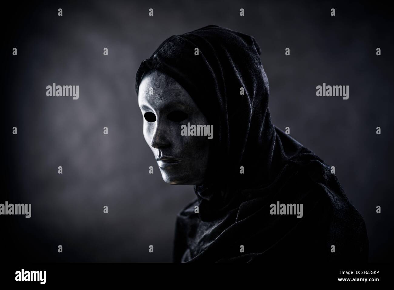 Scary figure with hooded cape in the dark Stock Photo - Alamy