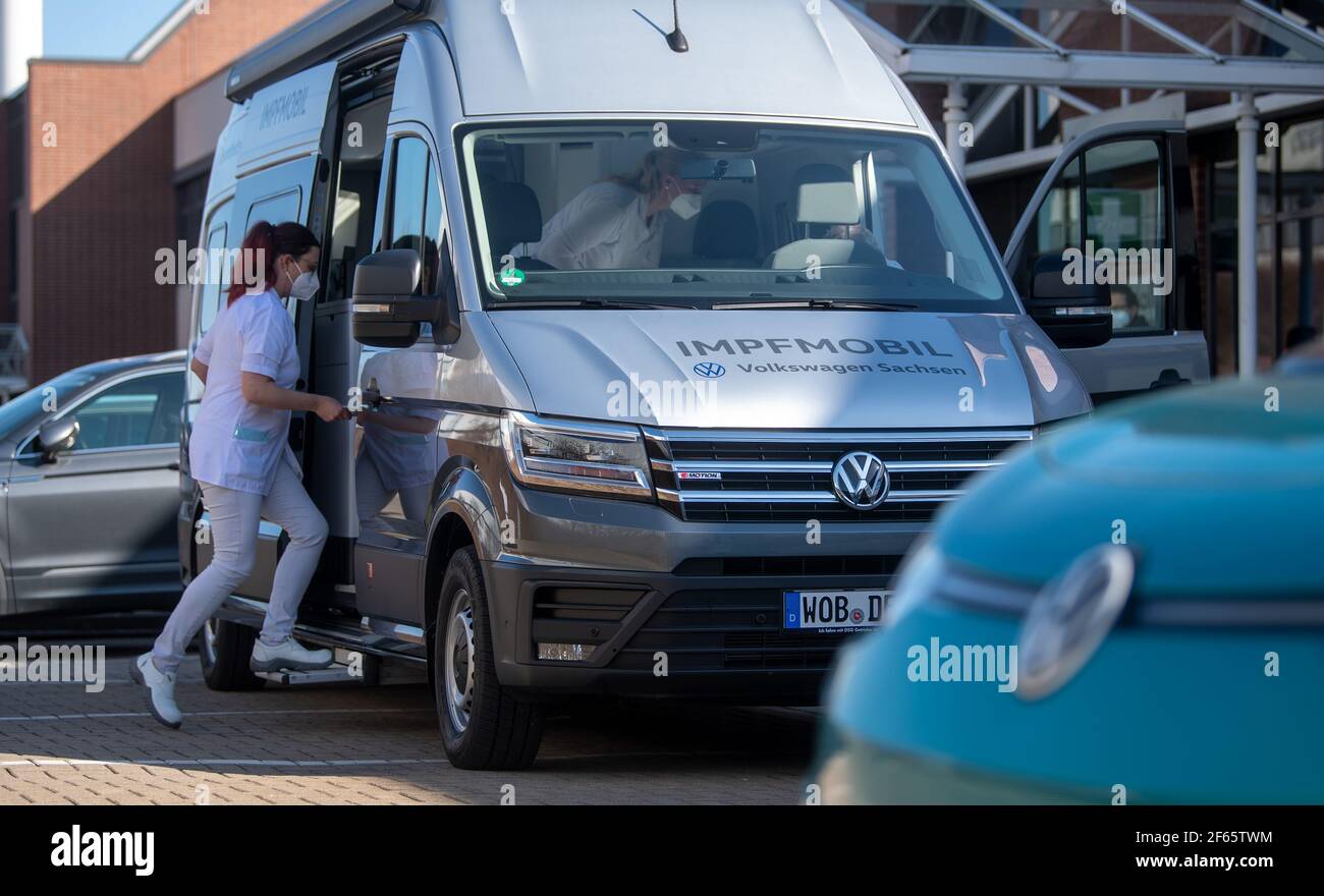 30 March 2021, Saxony, Zwickau: A nurse from Volkswagen's medical service  enters the new vaccination mobile on the premises of Volkswagen Sachsen in  Zwickau. On behalf of the German Red Cross, the