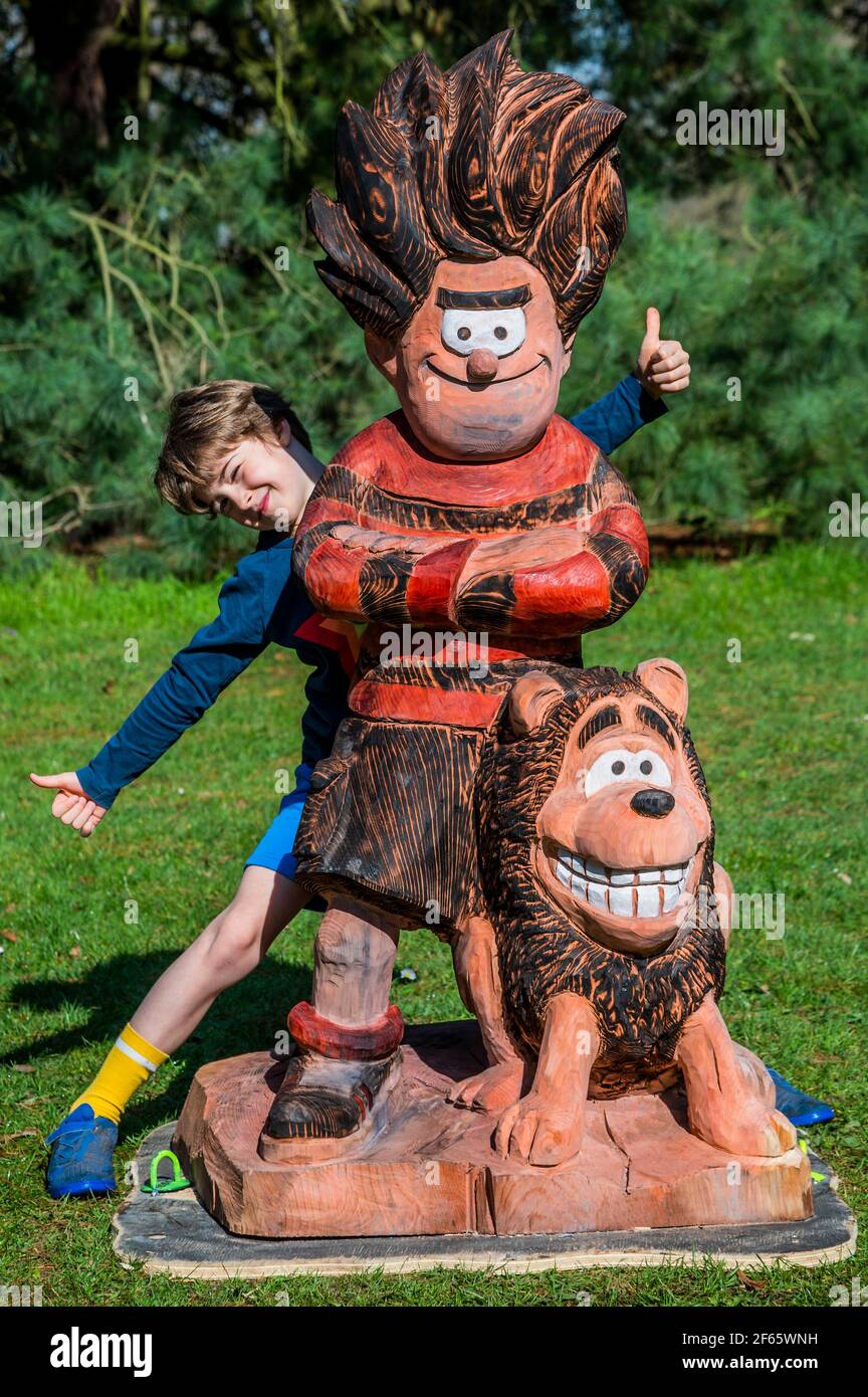 London, UK. 30th Mar, 2021. Celebrating the end of the trail with wood carvings of Dennis and Gnasher - Dennis and Gnasher's Big Bonanza, at Kew Gardens Easter festival, celebrating 70 years of Dennis the Menace in The Beano. The festival runs from Wednesday 31 March - Sunday 18 April and visitors will able to follow an exclusive, giant, 3D comic strip. The easing of the third 'lockdown' for the Coronavirus (Covid 19) has now moved to stage 1c in the UK. Credit: Guy Bell/Alamy Live News Stock Photo