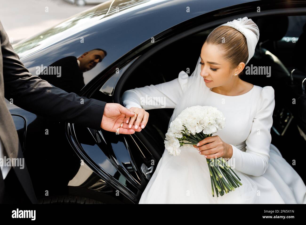 Bride's hand and the hand of the groom while getting out of the car or automobile. True affection. Stock Photo