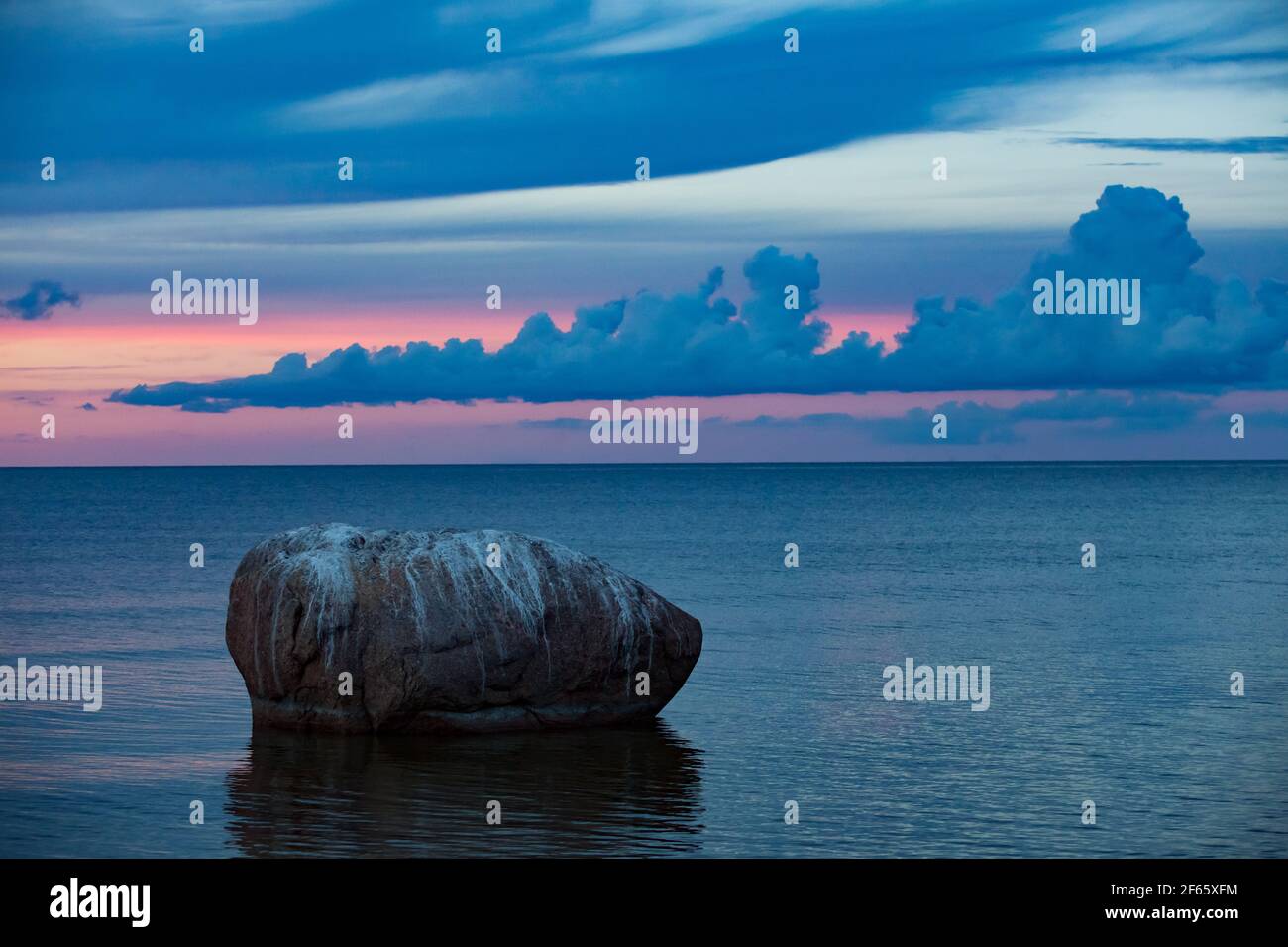 Estonia, Saaremaa island.Harilaid nature reserve. Sunset or sunrise on Baltic Sea. Big stone in water. Stock Photo