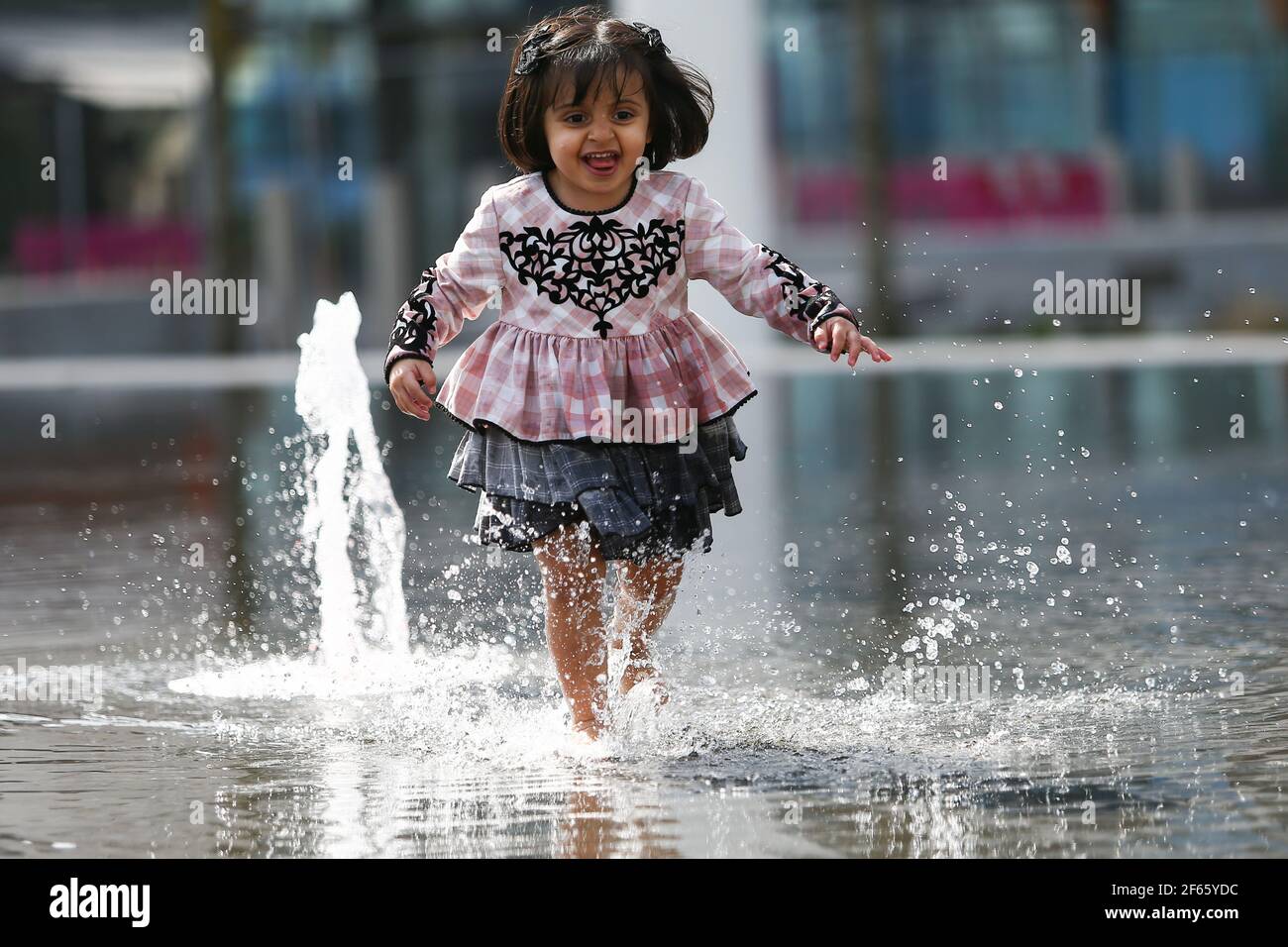 Birmingham, UK. 30th Mar, 2021. Two year old Hallah plays in the fountain in Centenary Square in Birmingham city centre. Credit: Peter Lopeman/Alamy Live News Stock Photo