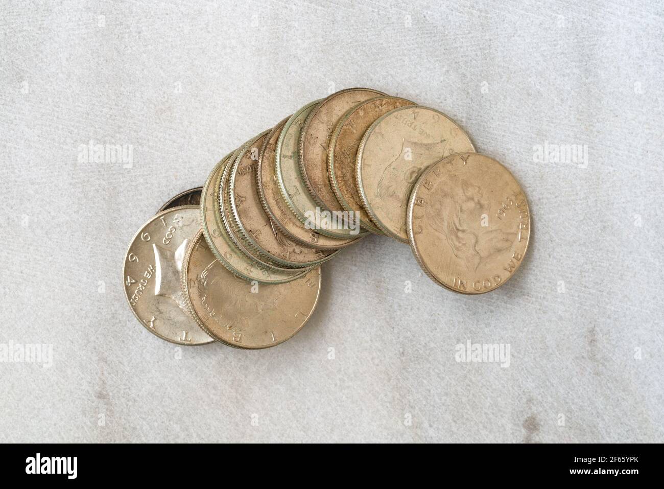 Several loose silver half dollar American coins on a marble surface. Stock Photo