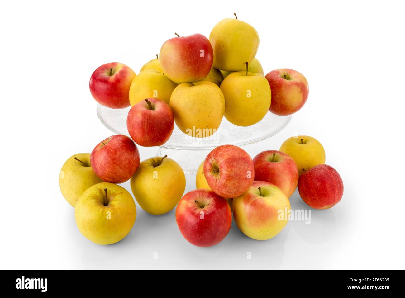 fuji apples and golden apples on clear glass raised plate, red and yellow fruits isolated on white background Stock Photo