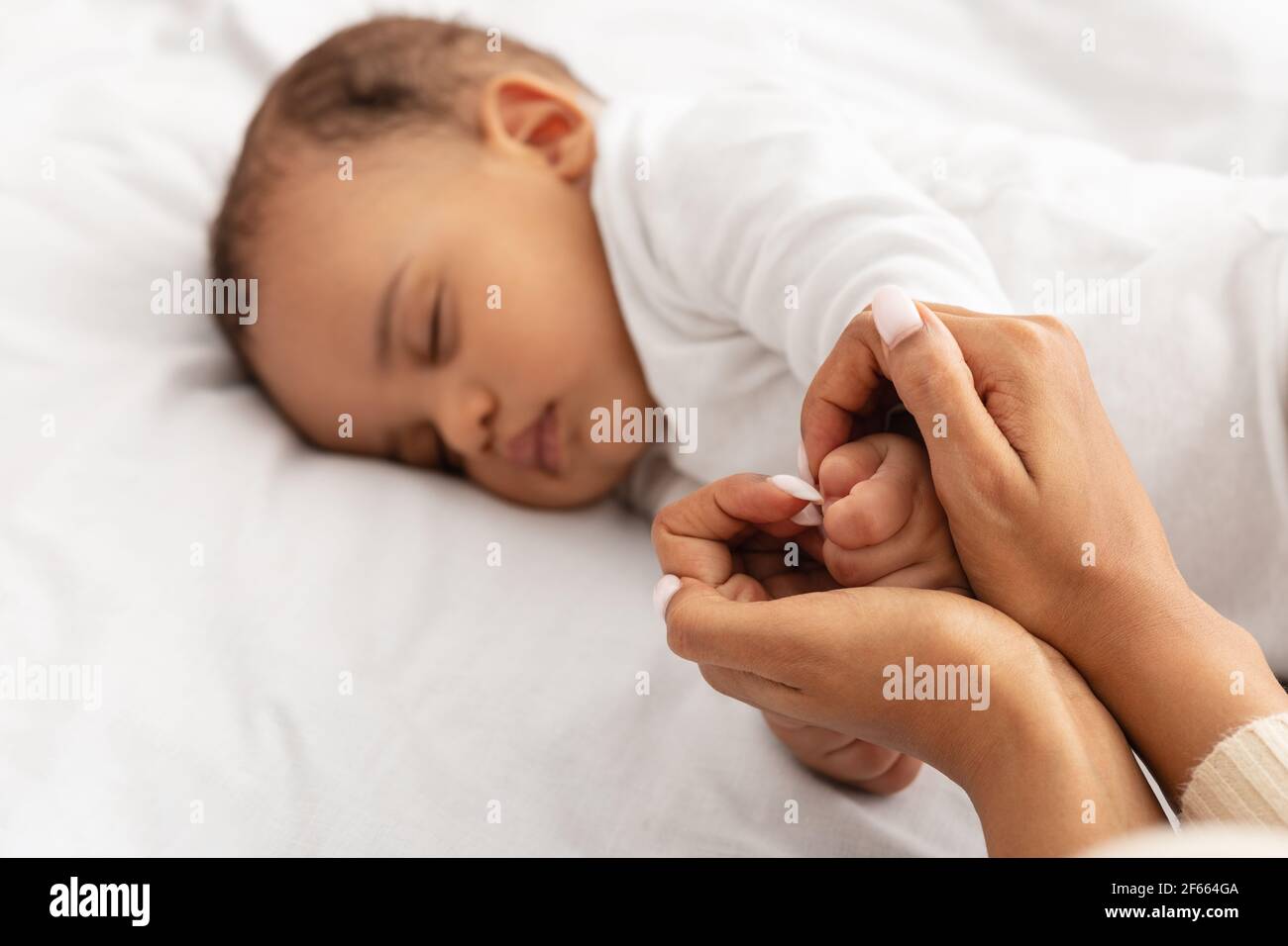 Loving Black Mom Holding Sleeping Baby's Hand Indoor, Selective Focus Stock Photo