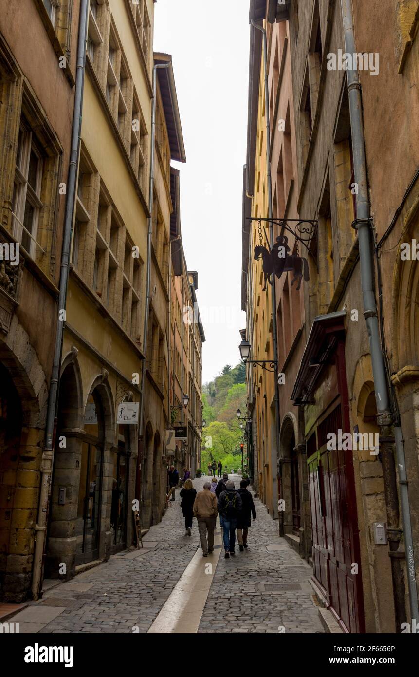 A narrow cobbled street between high, colourful old buildings in Vieux Lyon, France. Stock Photo