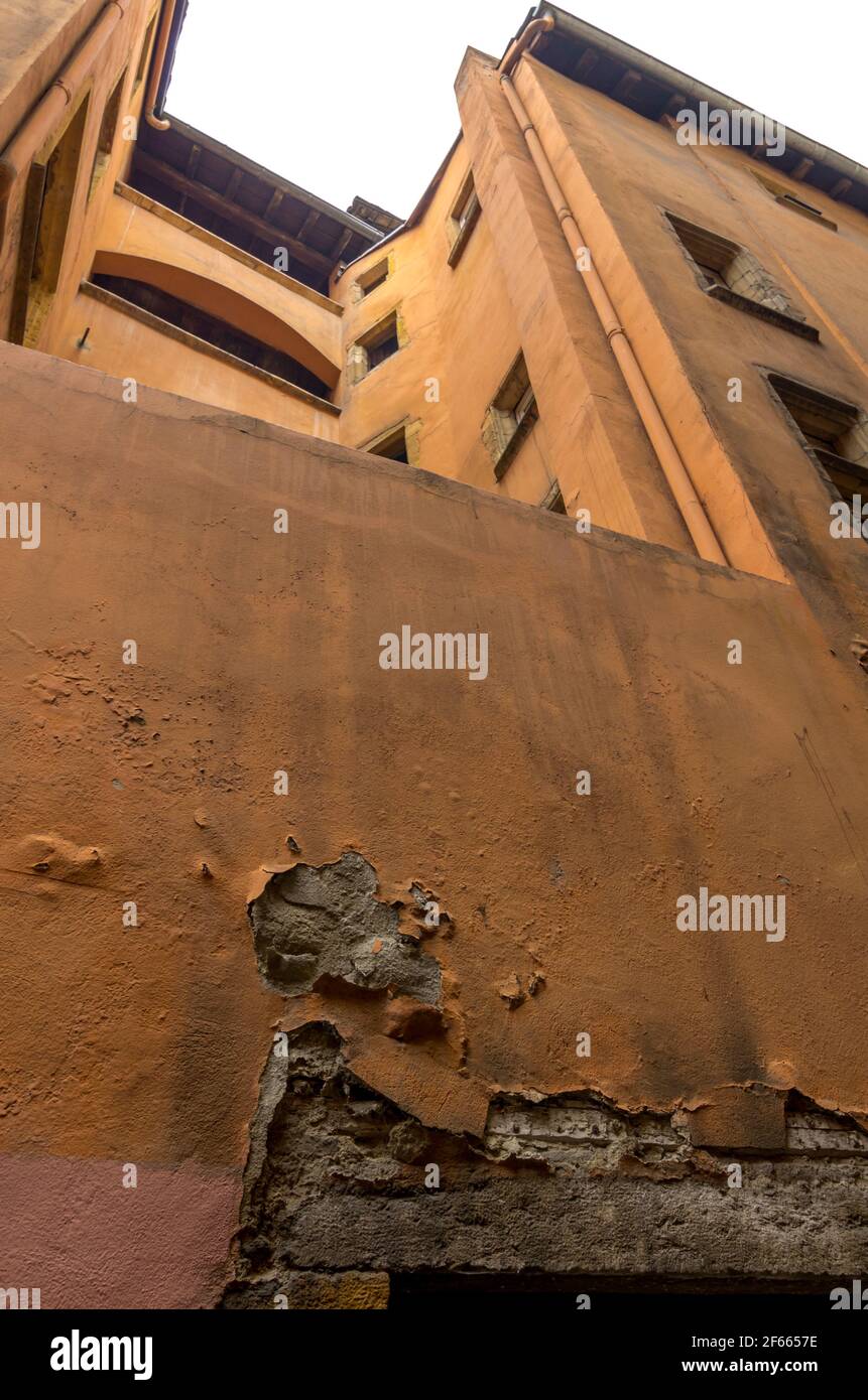 The decaying wall, orange plaster peeling off, of an old building in Vieux Lyon, France Stock Photo