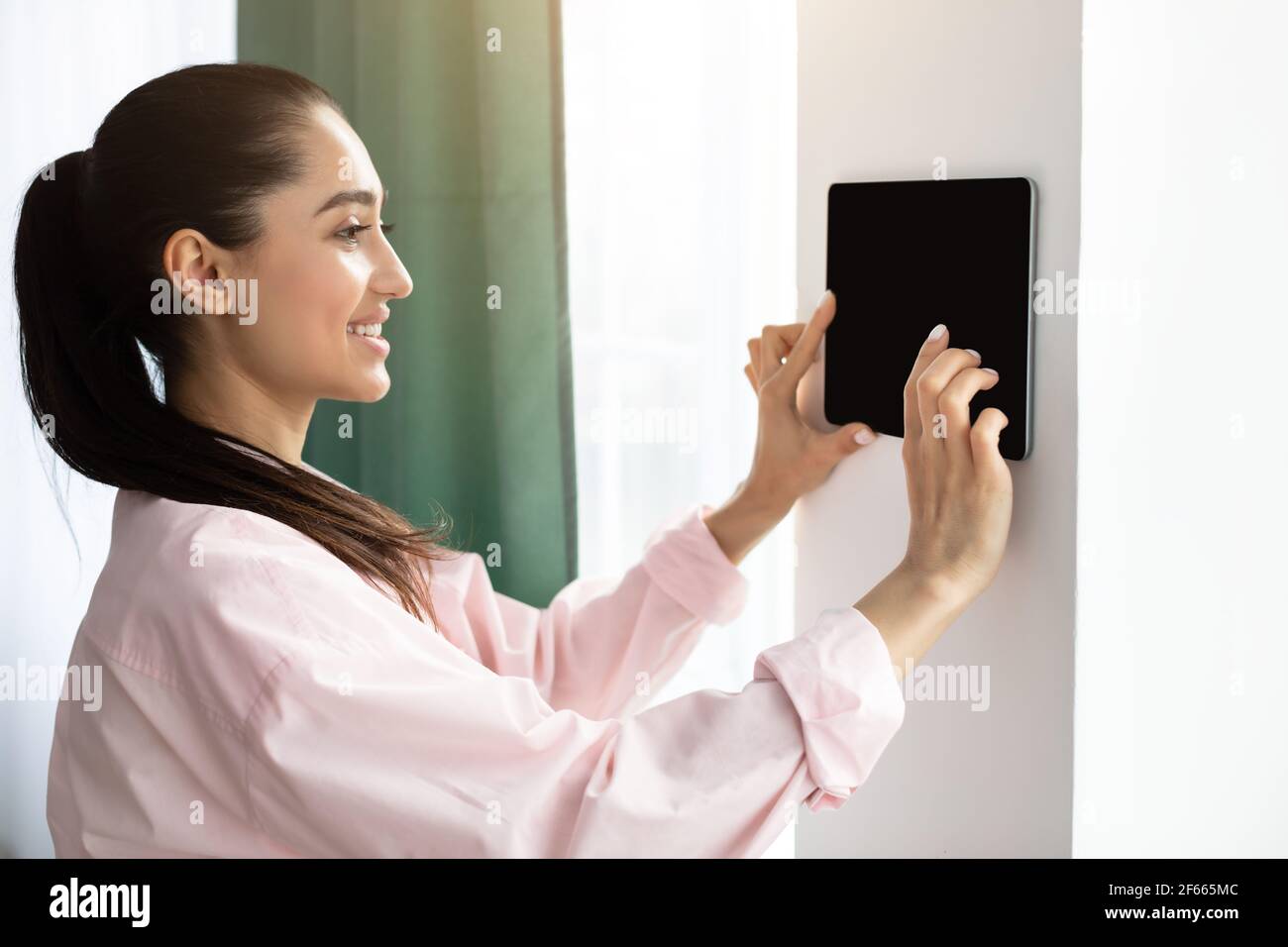 Woman using smart wall home control system Stock Photo