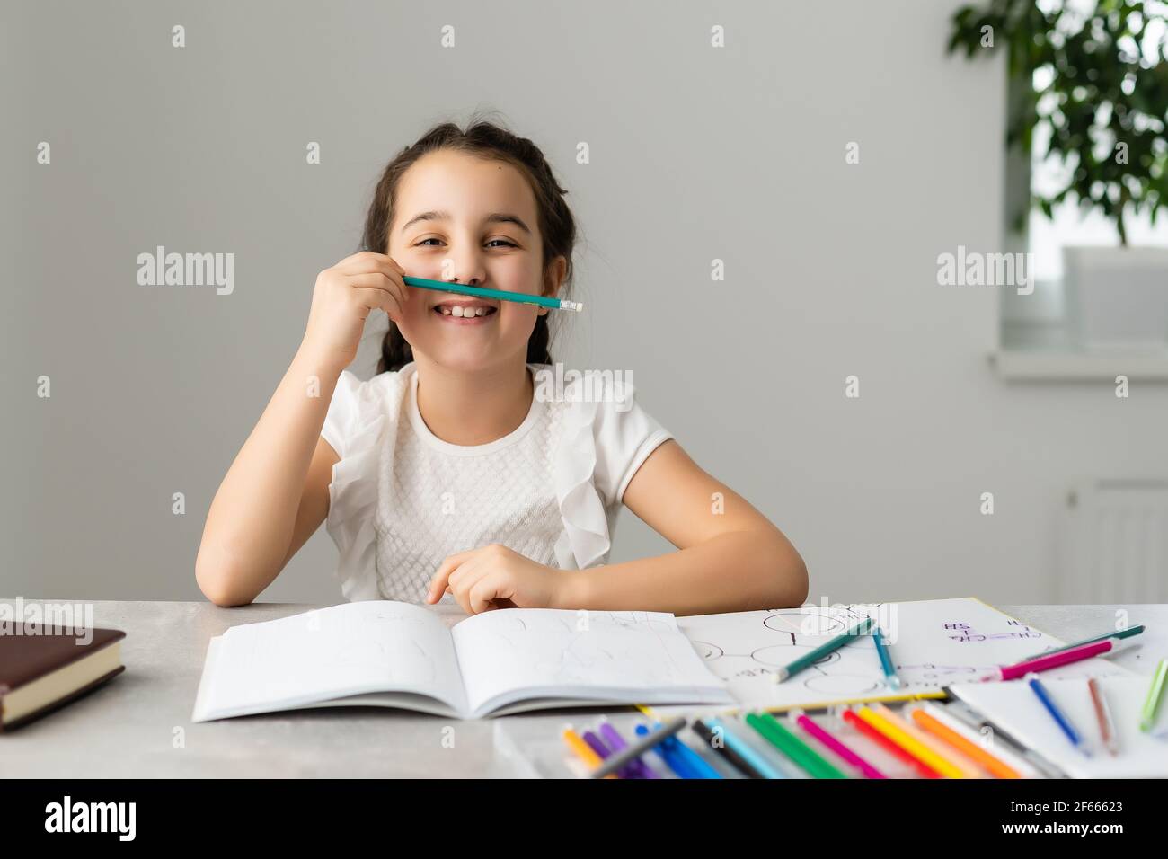 Cute little girl studying at home and smiling Stock Photo - Alamy