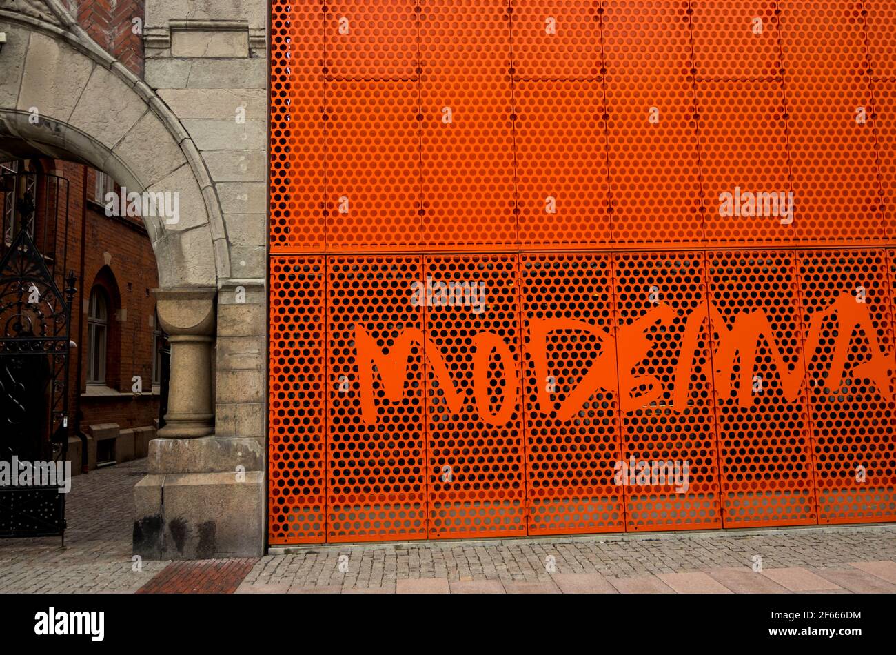 The exterior of the annexe, Moderna Museet / Museum of Modern Art in Malmo, Swedem showing the bright orange metal grill by the stone arched entrance Stock Photo