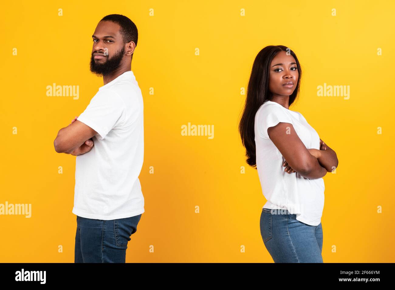 Afro couple standing back to back, yellow studio wall Stock Photo - Alamy