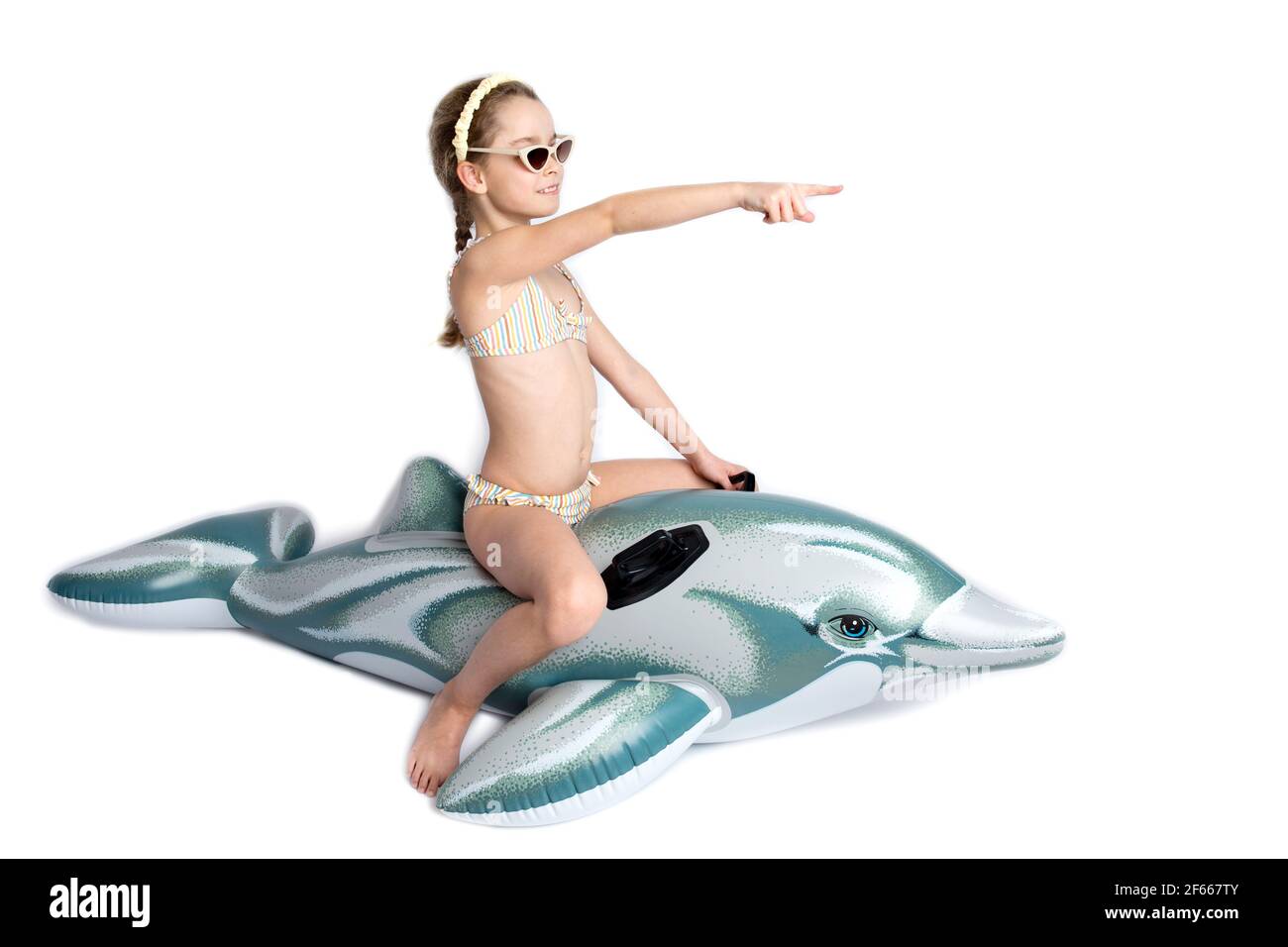 Happy child in a in a bathing suit on an inflatable dolphin. Coronavirus pandemic and healthy lifestyle concept. Stock Photo