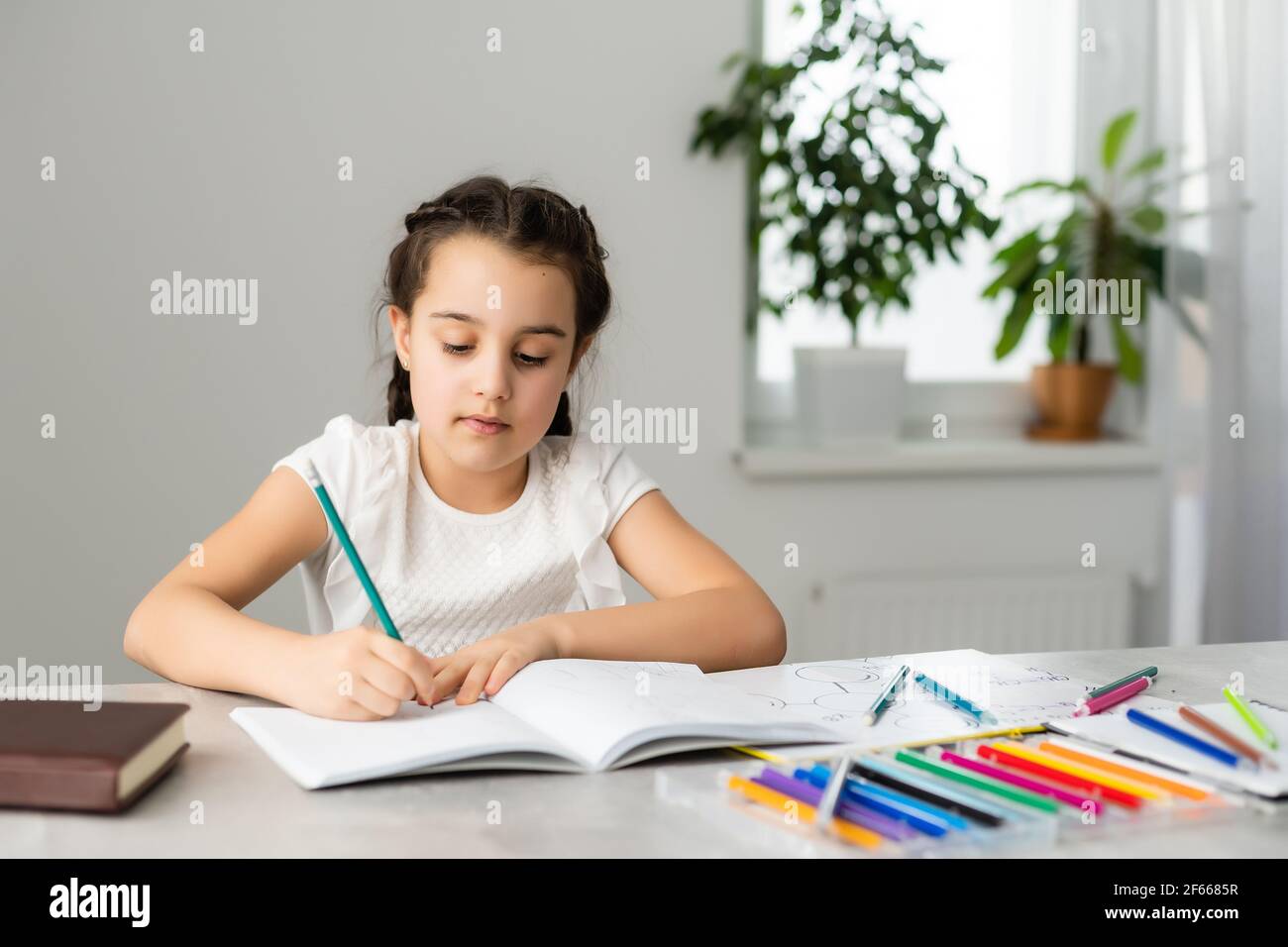 Cute little girl studying at home and smiling Stock Photo - Alamy