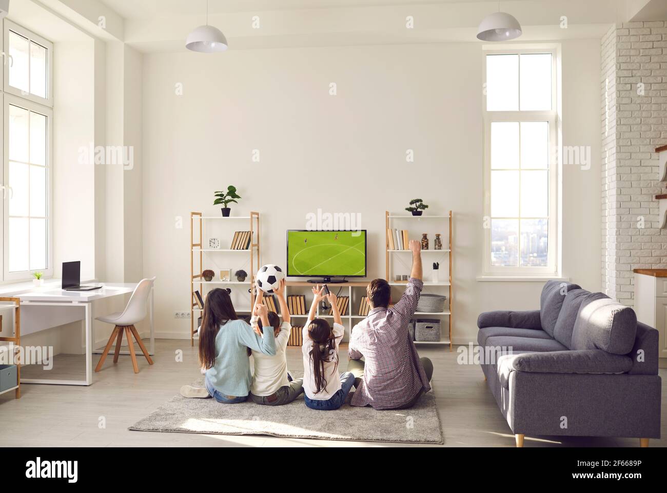 Happy excited family with children watching soccer match on tv at home Stock Photo