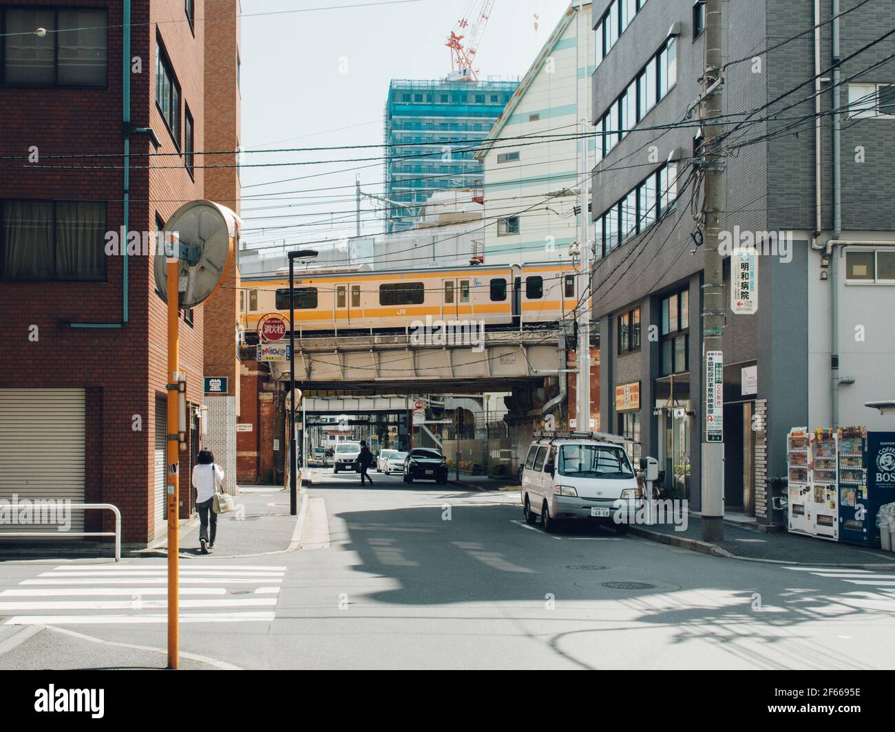 Tokyo, Japan - Small street with the train running on the elevated railway. Quiet side street with a few people and cars. Stock Photo