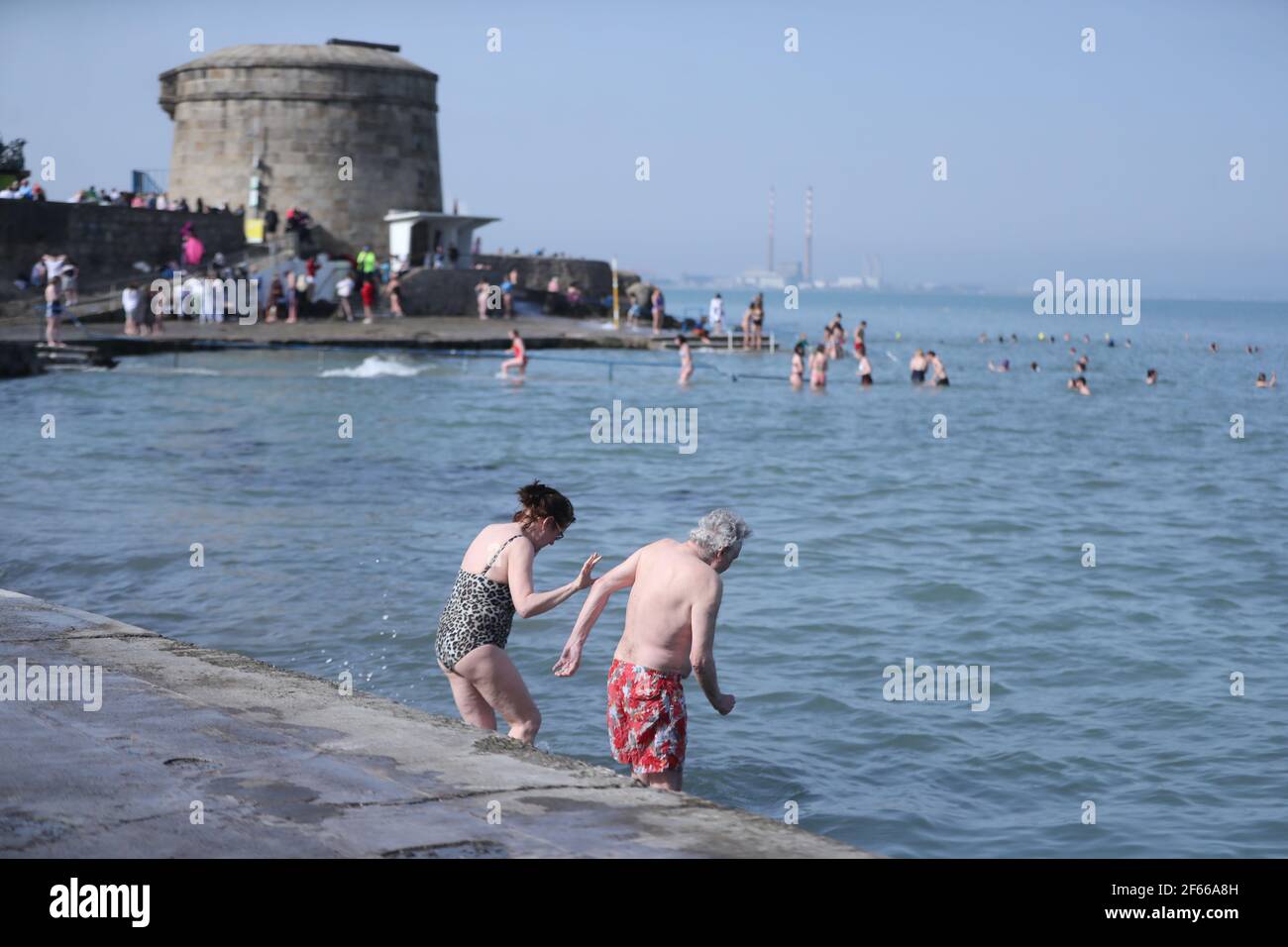 A couple enjoy the warm weather at a swimming spot by the Martello Tower at Seapoint Beach near Dublin. Picture date: Tuesday March 30, 2021. Stock Photo
