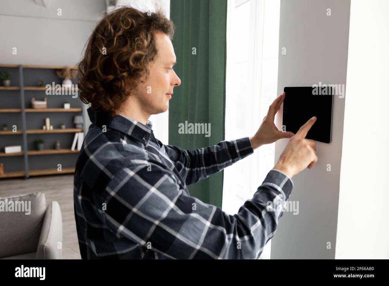 Man Using Smart Home Control System On Digital Tablet Indoors Stock Photo