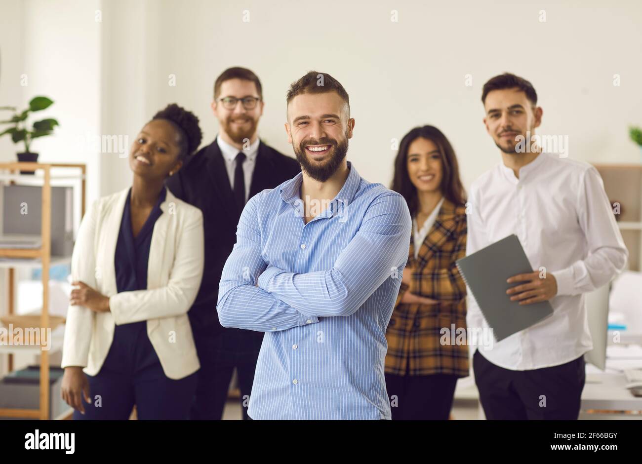 Happy smiling handsome caucasian manager or team leader standing with employees Stock Photo