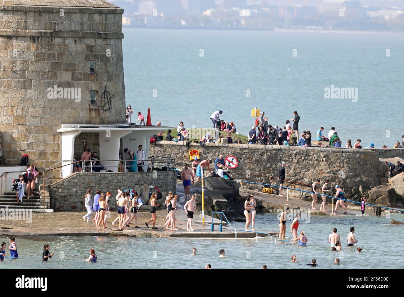 People enjoy the warm weather at a swimming spot by the Martello Tower at Seapoint Beach near Dublin. Picture date: Tuesday March 30, 2021. Stock Photo
