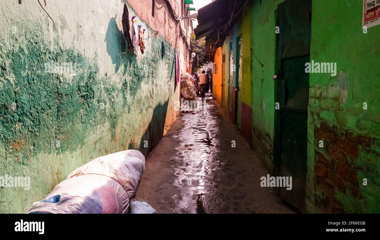 Kolkata, West Bengal, India - January 2018: A narrow grungy alley passing through a slum with the streets wet with water in the Kumartuli area of the Stock Photo