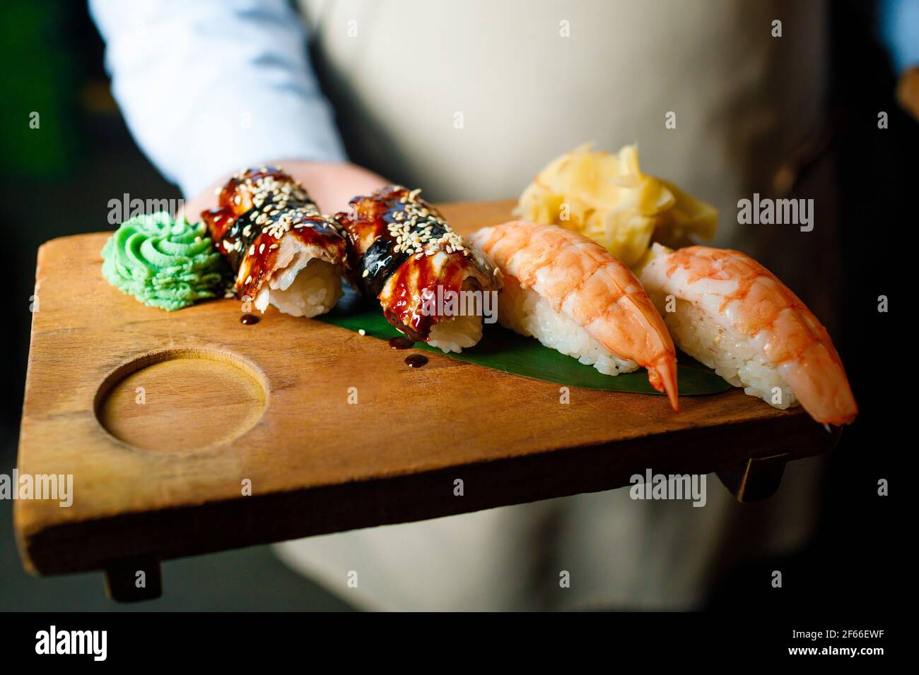 https://c8.alamy.com/comp/2F66EWF/the-waiter-is-holding-sushi-on-a-wooden-board-2F66EWF.jpg