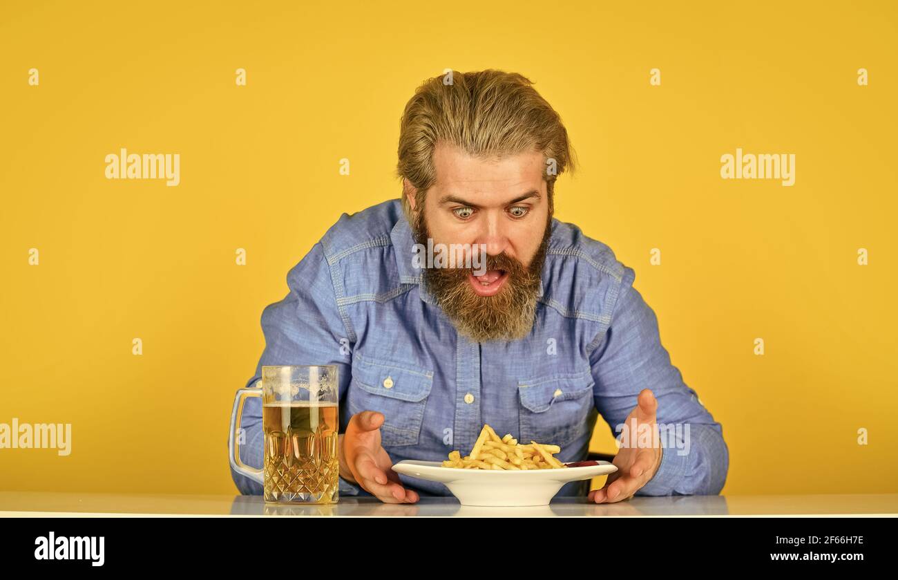 man with fast food. beer and french fries in restaurant. eating and drinking at bar. hipster relax in tavern. bearded guy having snack. lazy man Stock Photo